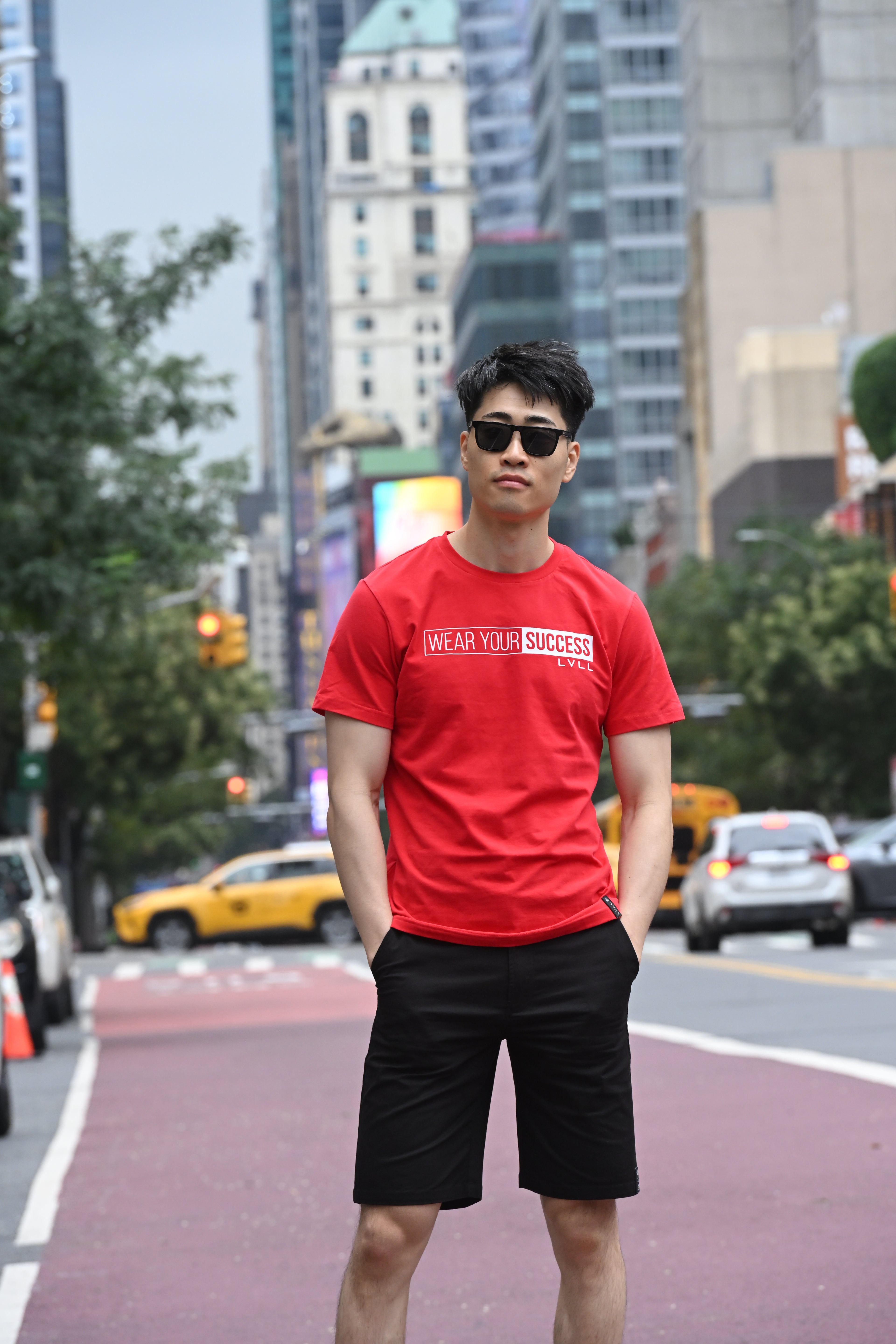 Person wearing a LVLL"s red t-shirt, black sunglasses and black shorts in grand central New York.